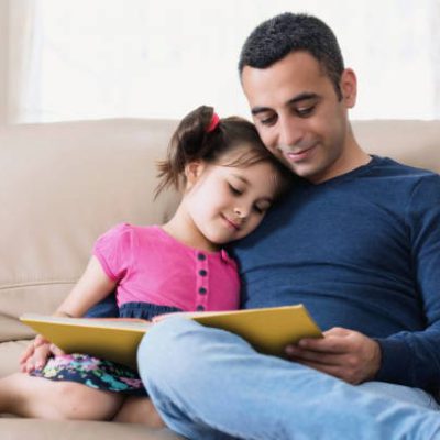 Little girl and father are enjoying reading book together
